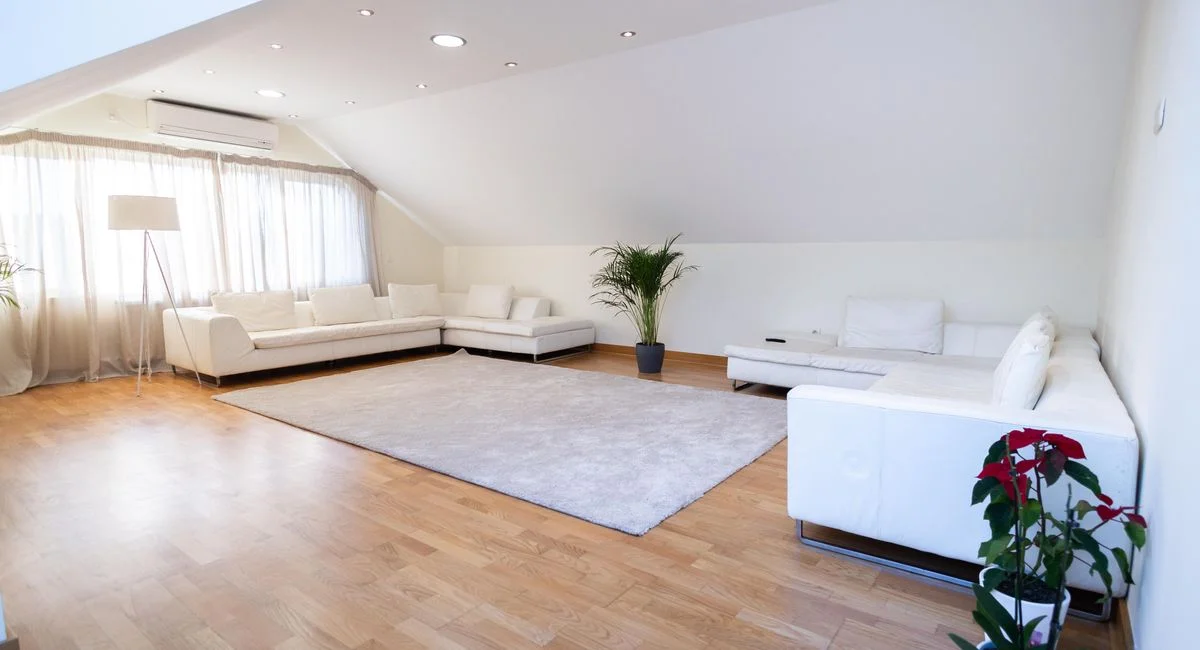 Bright modern living room with white sofas and wooden floor, ideal for relaxation.