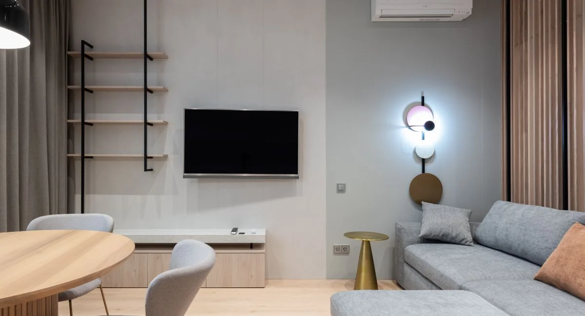 Comfortable living room furnished with big sofa placed near TV and shelf with curtains