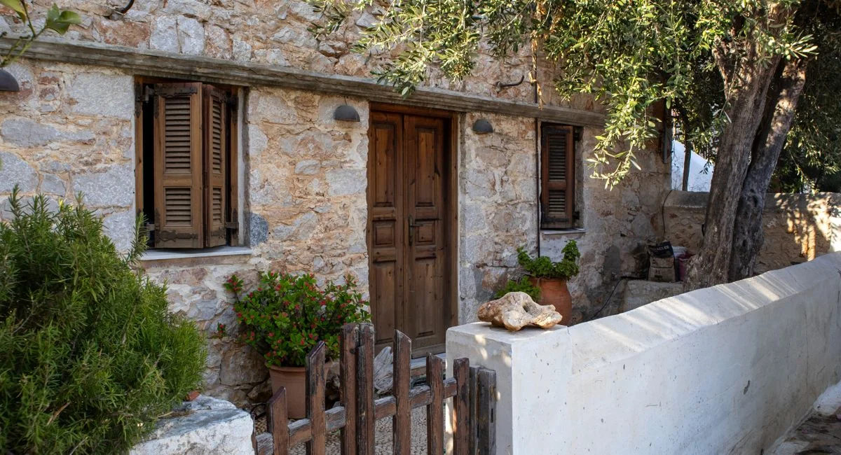 Beautiful rustic stone house with wooden shutters and a welcoming entrance surrounded by greenery.