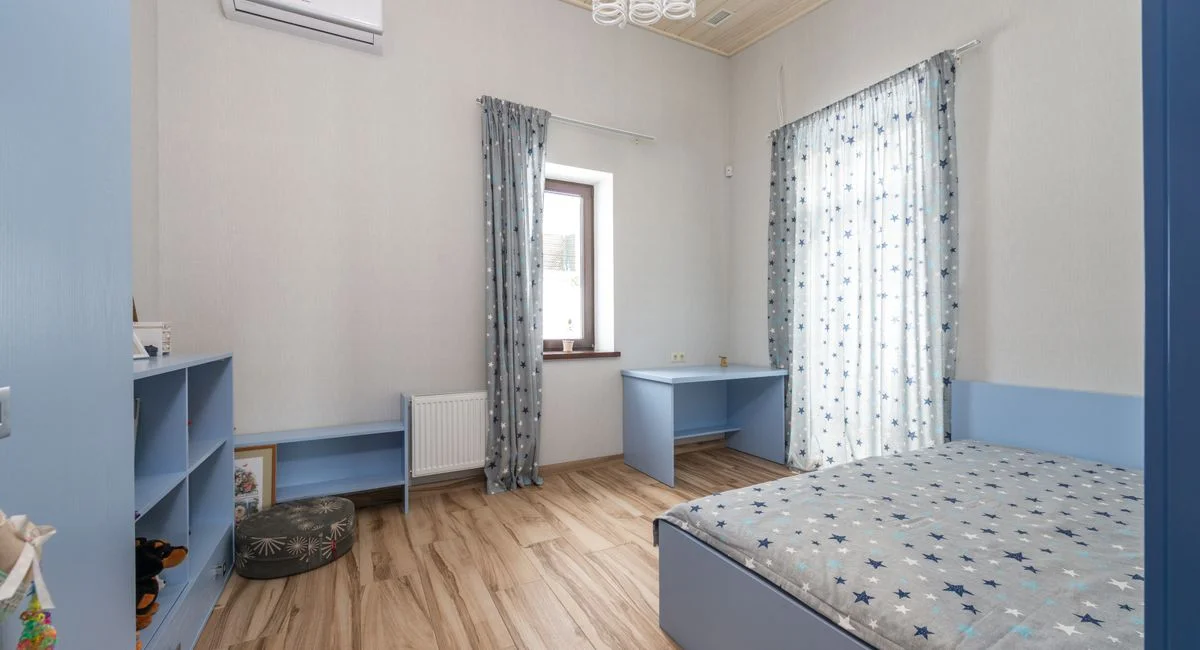 A serene and cozy bedroom with blue decor featuring wooden flooring and natural lighting.