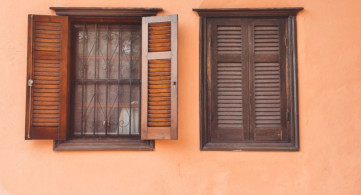 Charming wooden windows on a peach-colored wall in Thessaloniki, Greece. Warm and inviting Mediterranean style.