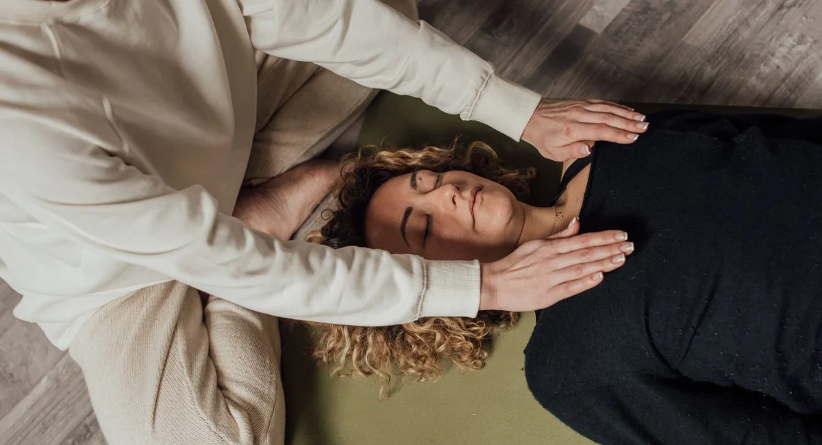 A woman receiving a holistic healing session indoors, focusing on relaxation and spiritual wellbeing.