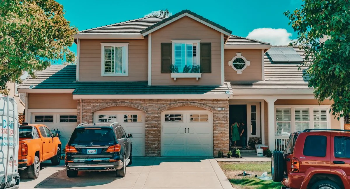 Charming suburban house with parked cars and vibrant summer setting.