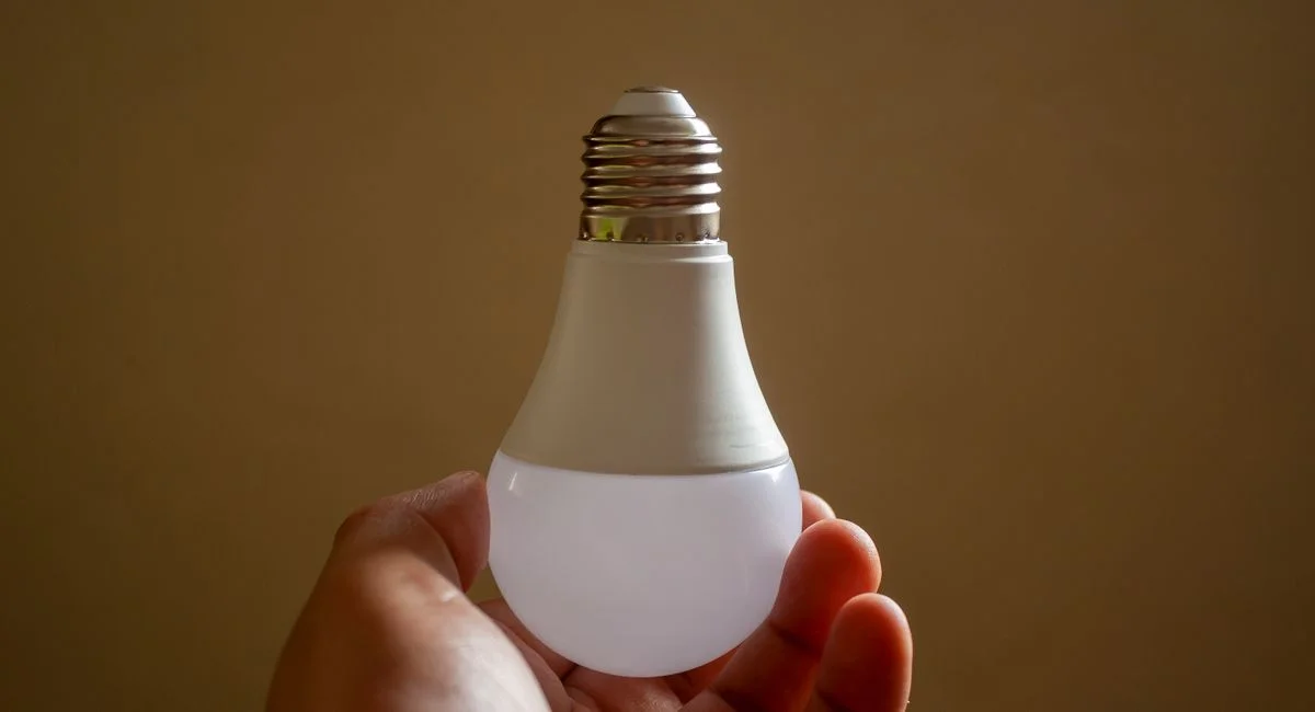 Close-up of a hand holding an energy-efficient LED bulb, emphasizing sustainability and innovation.