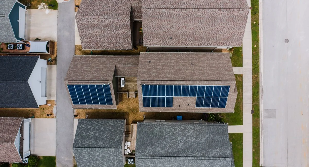 Top-down view of suburban houses featuring solar panels on roofs, showcasing renewable energy use.