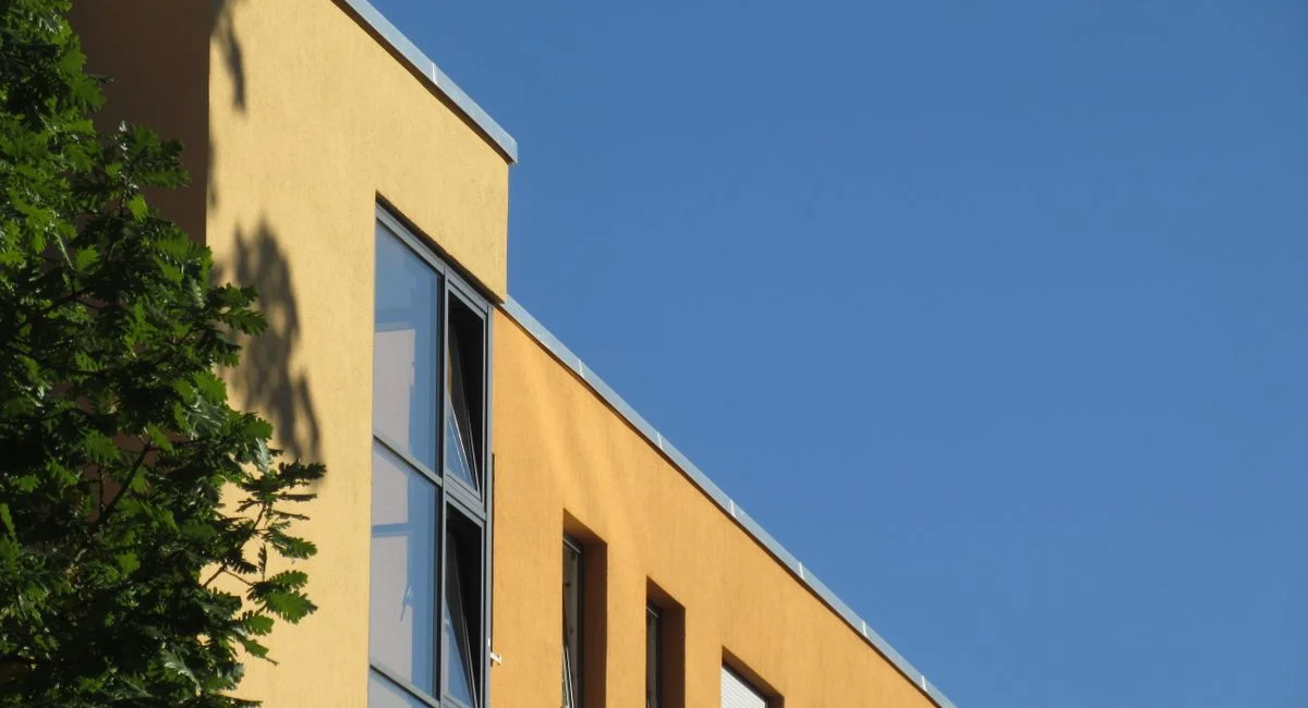 Angle view of a yellow building with windows against a bright clear blue sky.