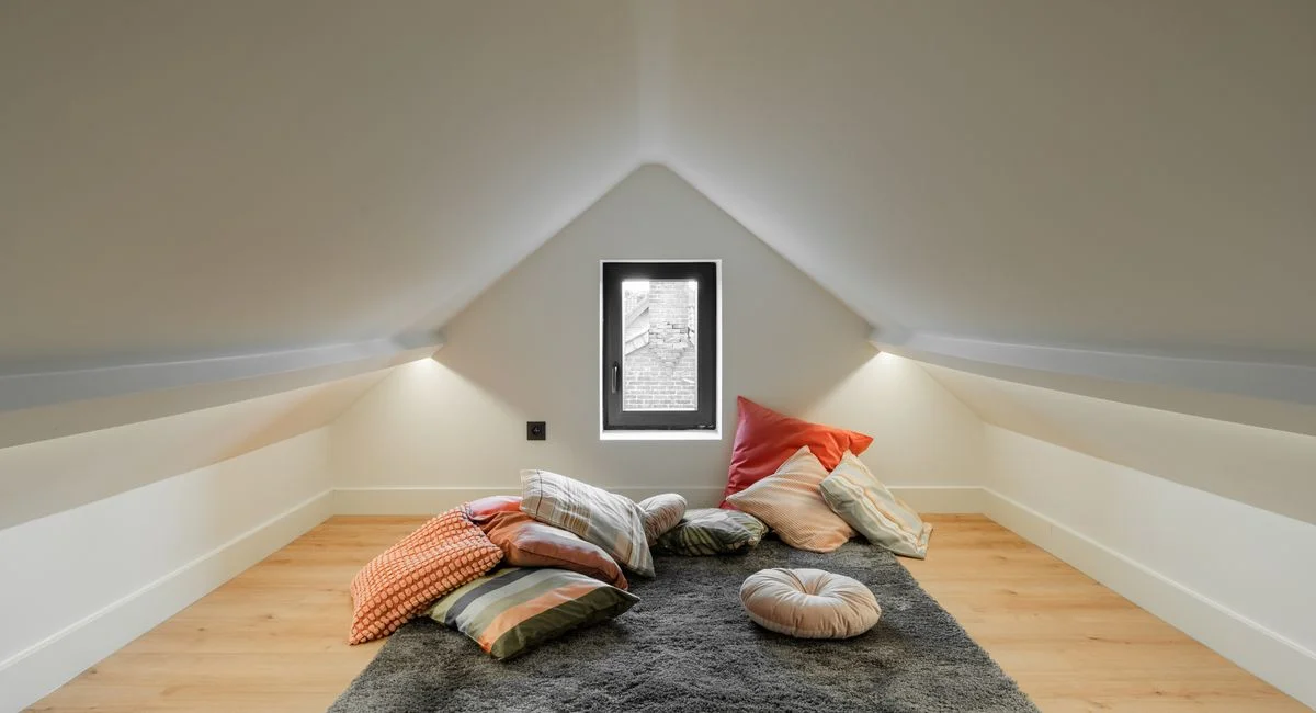 A serene attic room featuring colorful pillows and soft lighting, perfect for relaxation.