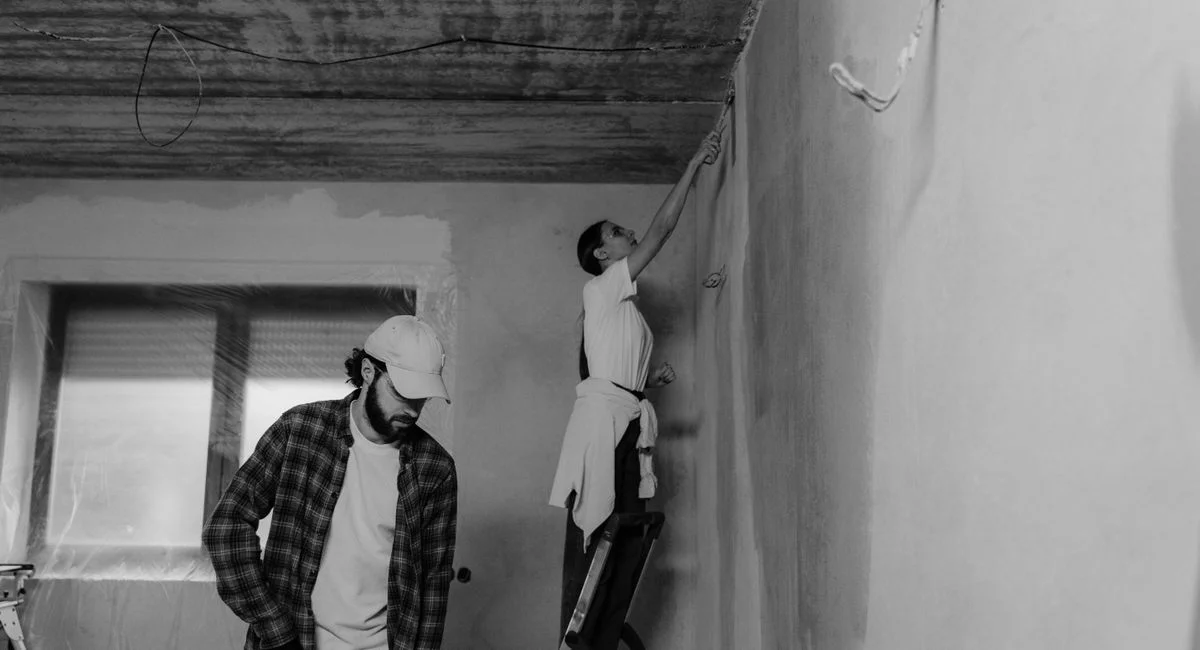 Black and white photo of a couple painting a room during home renovation.