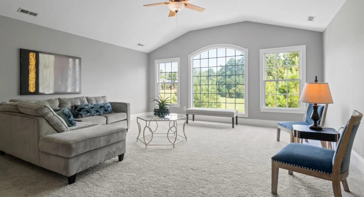Contemporary living room with neutral tones, large windows, and modern furniture.