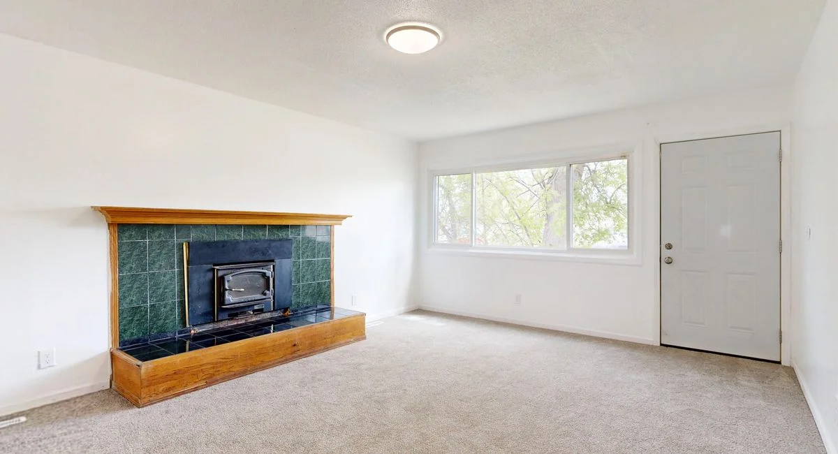 Bright empty living room featuring a modern fireplace and large window view.