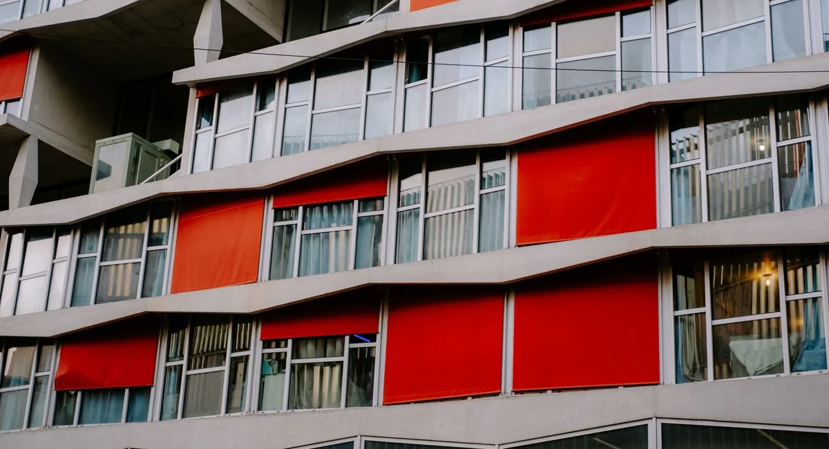 Contemporary building with unique red paneling and large glass windows, creating a striking architectural design.