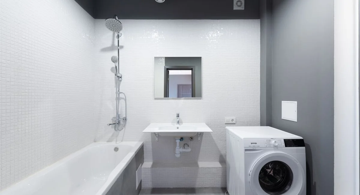 Modern bathroom design featuring bathtub, sink, and washing machine.