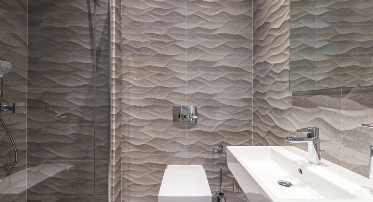 Sleek bathroom featuring textured walls, a glass shower, and a modern sink.