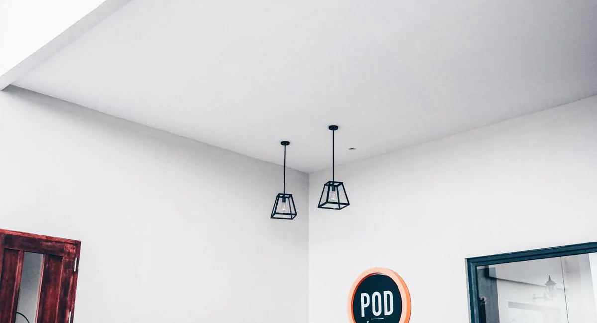 Modern minimalist interior featuring geometric pendant lights and a POD sign.