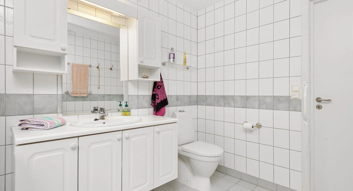 Bright and clean modern bathroom with white tiles and minimalistic decor.