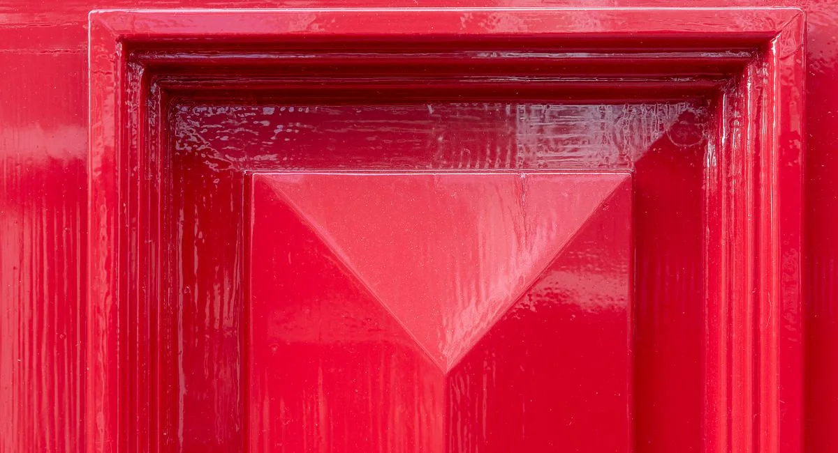 Close-up of a vibrant red door featuring a geometric design, perfect for architecture and design themes.