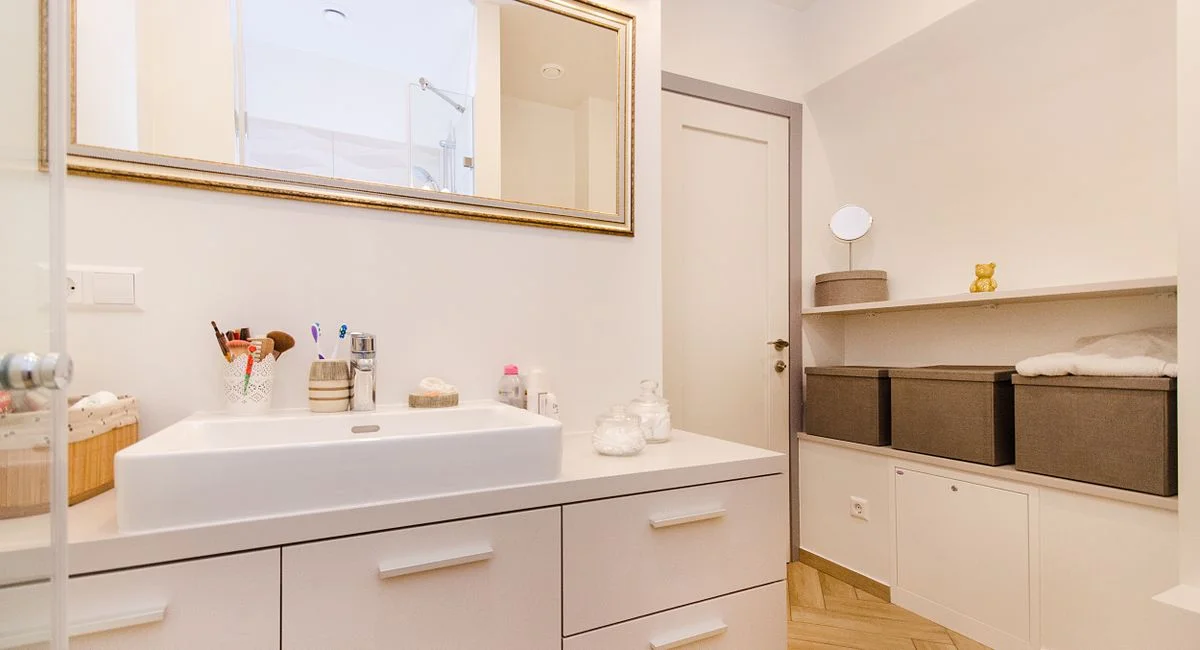 Stylish bathroom interior with sleek white vanity and large mirror.
