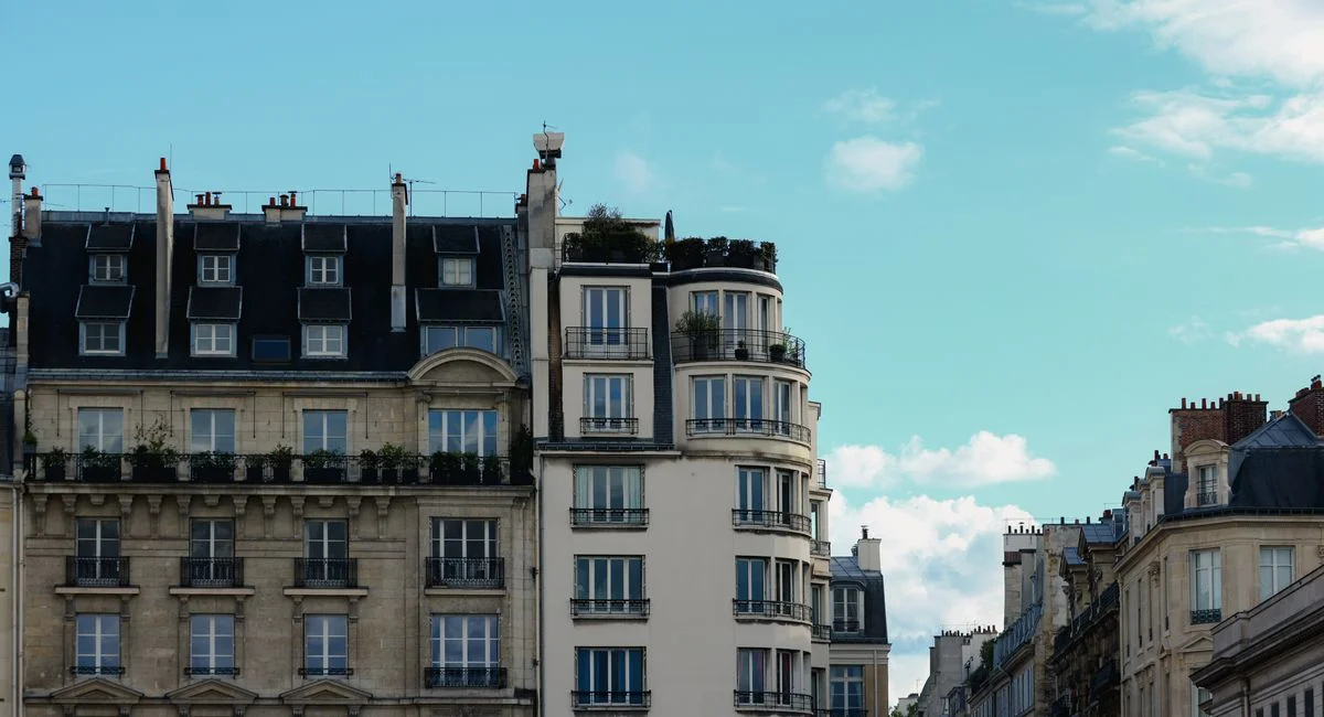 Elegant Parisian buildings with classic architecture under a bright blue sky.