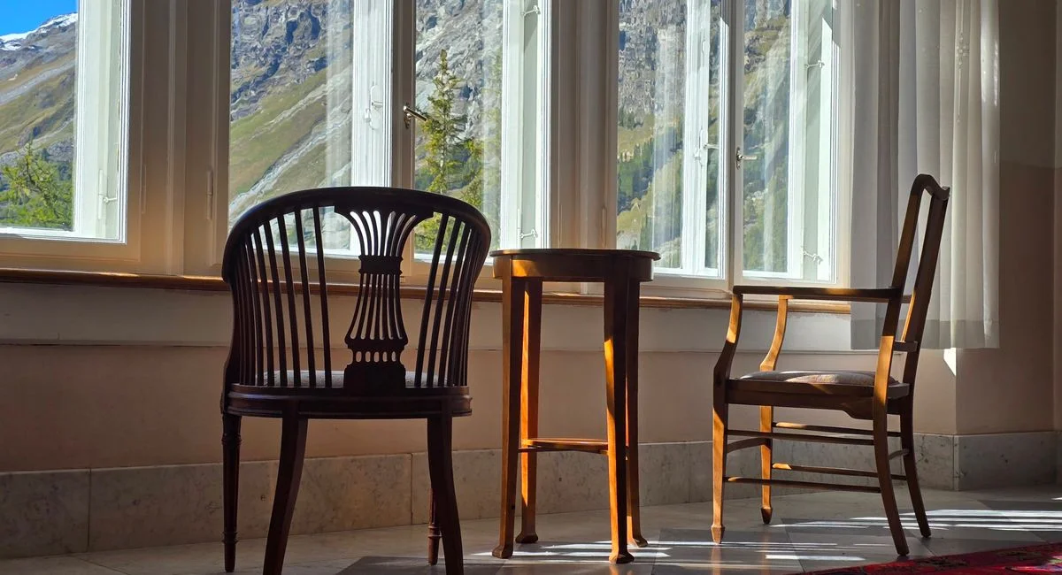 Sunlit room with elegant chairs overlooking a mountainous landscape, perfect for relaxing.