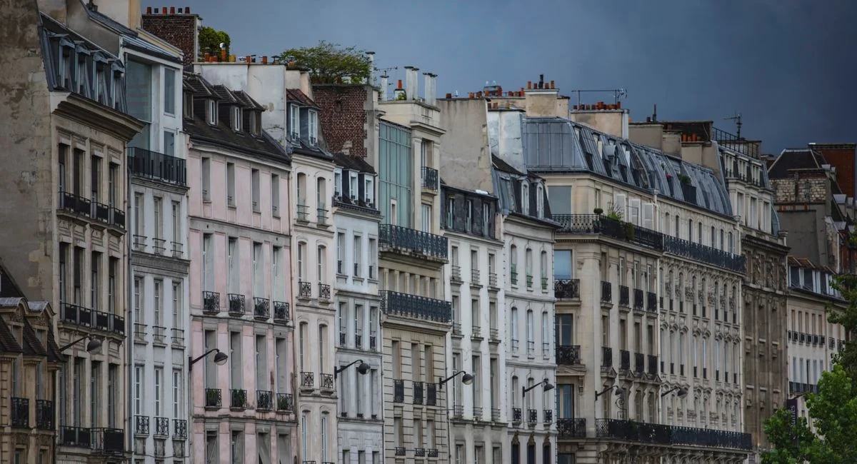 Row of traditional Parisian buildings under a dramatic, cloudy sky.