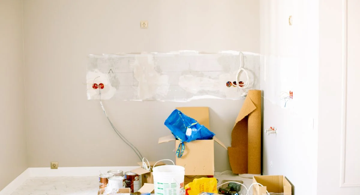A room undergoing renovation with tools, supplies, wiring, and paint cans scattered around.