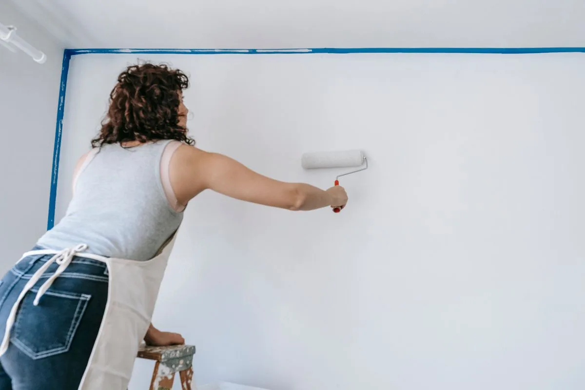 Une personne peint un mur de son logement avec un rouleau